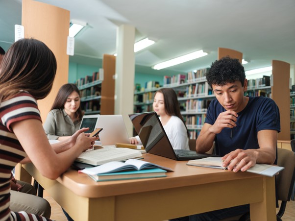 Man studying in library. Stress, school, therapy and assessment support at Through the Woods Psychology.