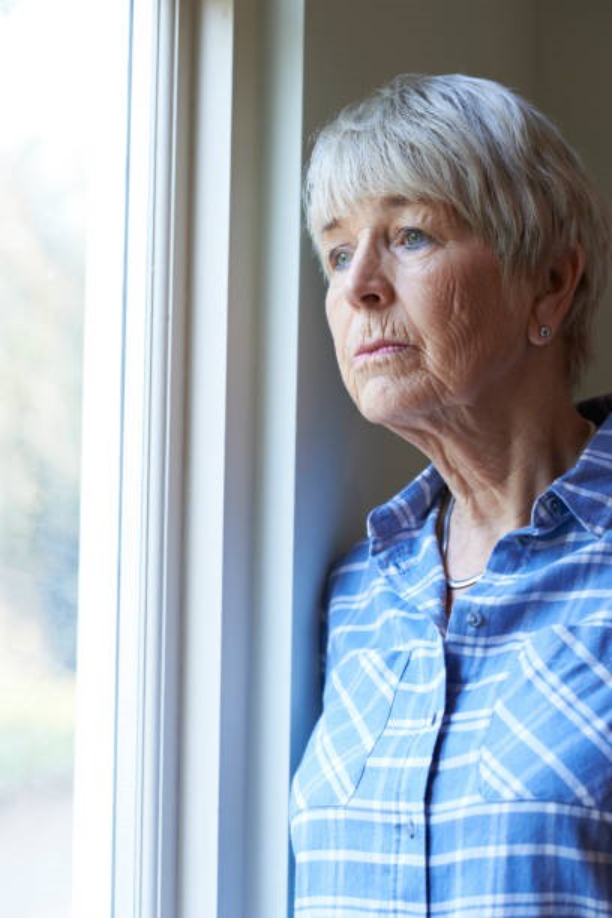 Elderly woman looks out window